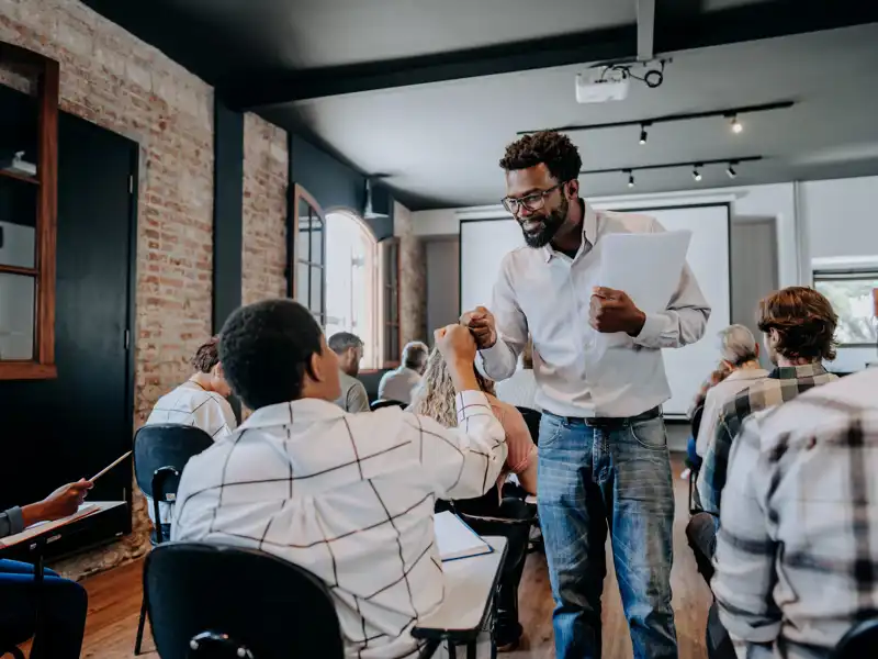 Teacher fist pumping adult students in the classroom.
