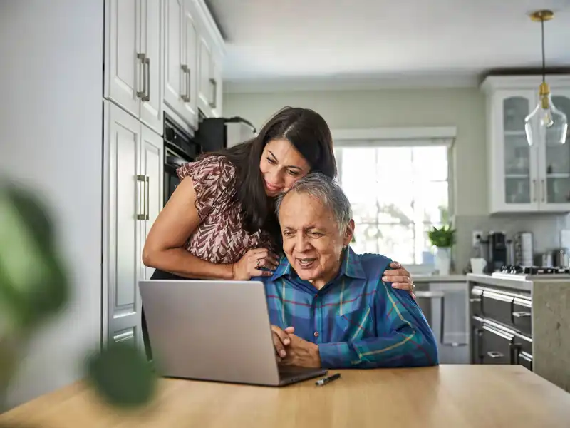 Daughter assisting father on how to use the computer.