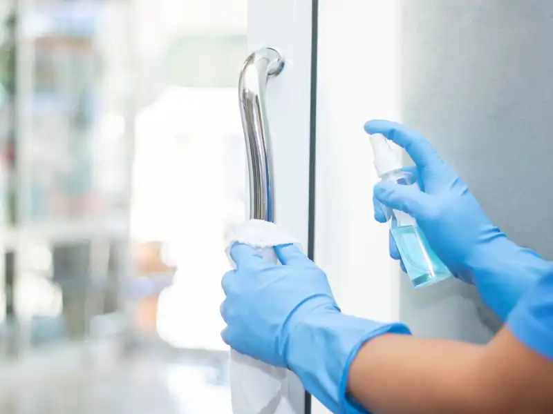 Person cleaning glass door in rubber gloves