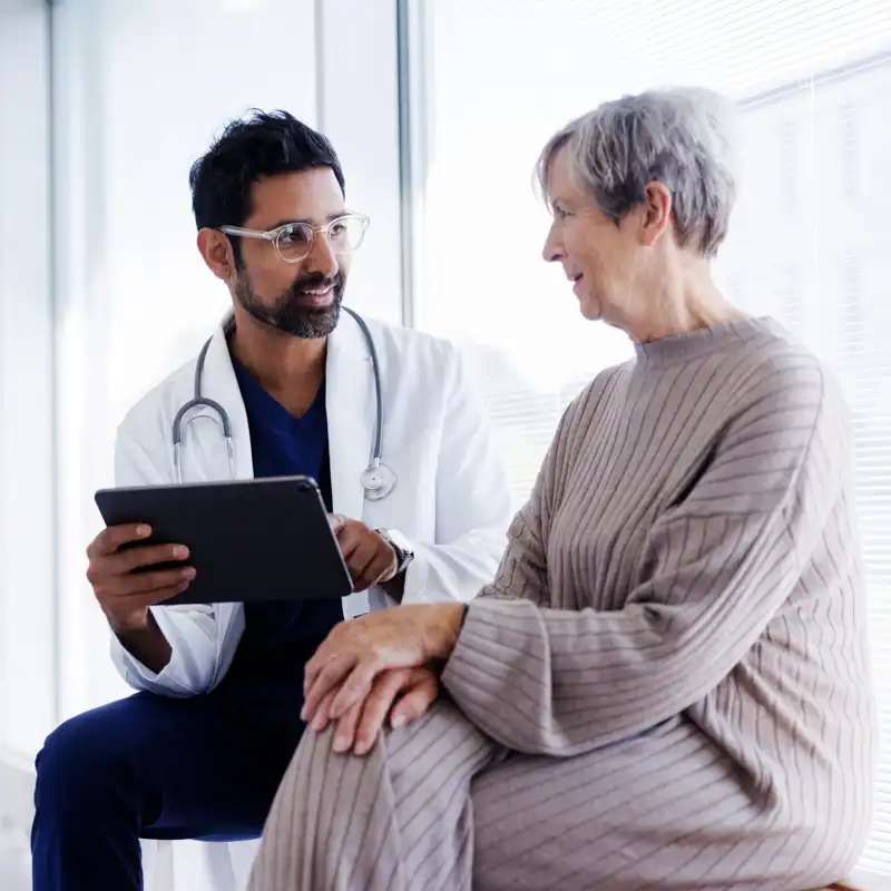 Doctor and patient in conversation, looking at digital tablet.
