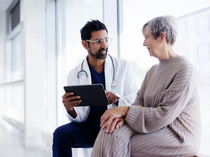 Doctor and patient in conversation, looking at digital tablet.