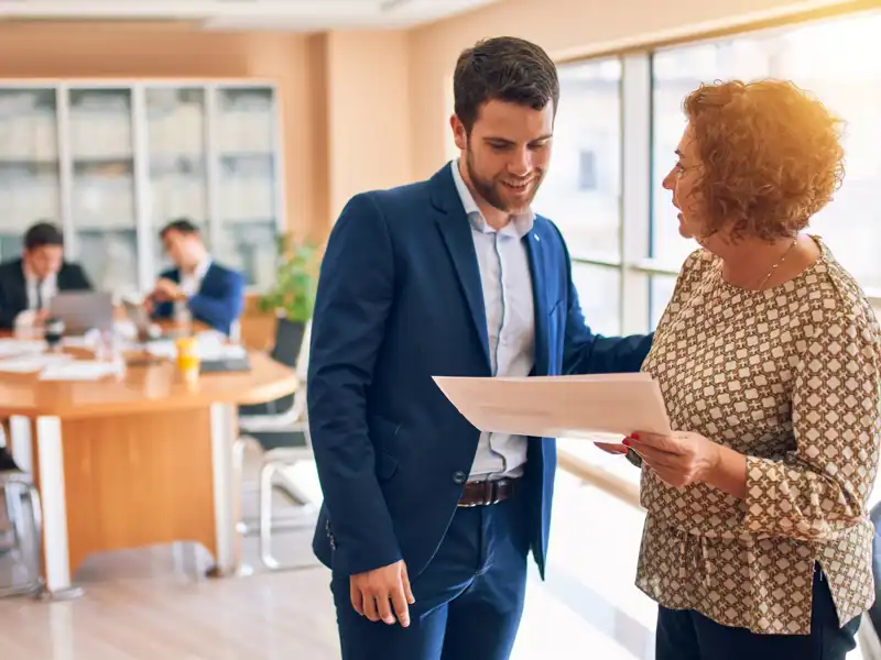 Man and woman talking in an office holding a piece of paper