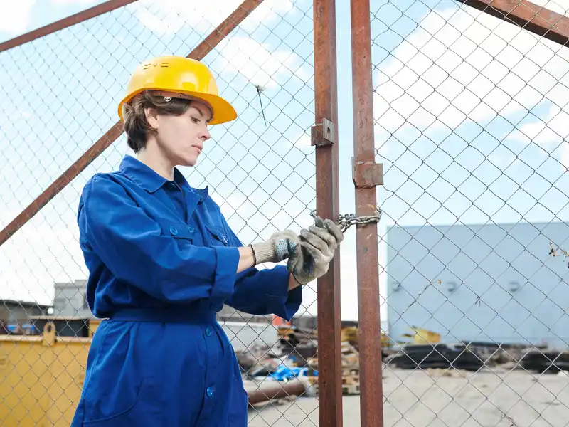 female construction worker unlocking gate on a job site