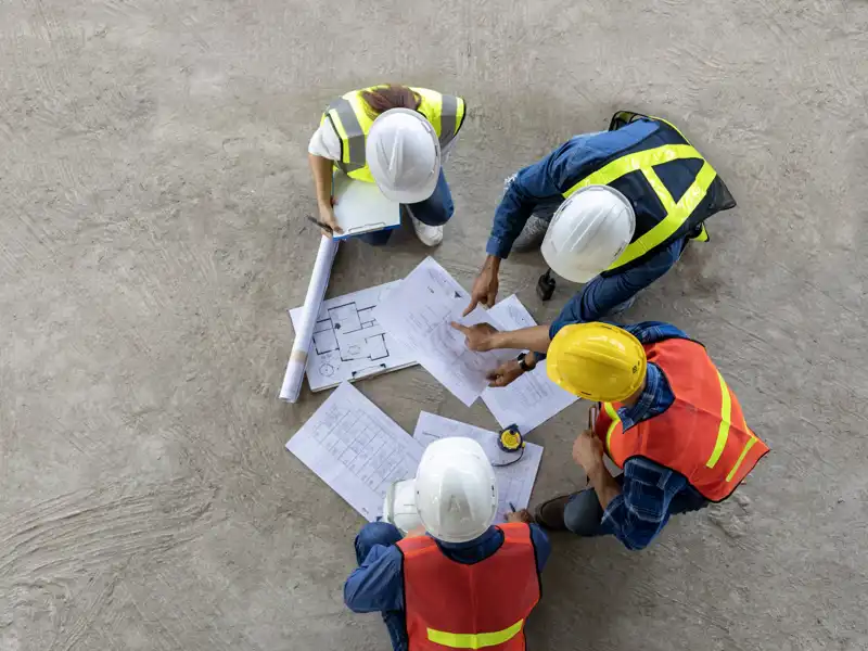 aerial view of construction workers looking at blueprints