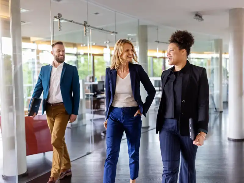 Three people walking down a hallway, smiling.