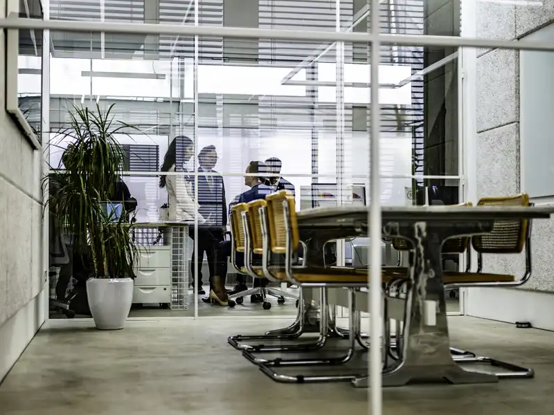 Group in a glass conference room, talking.