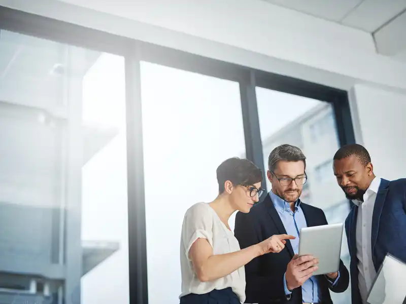 Three professionals looking at a tablet.