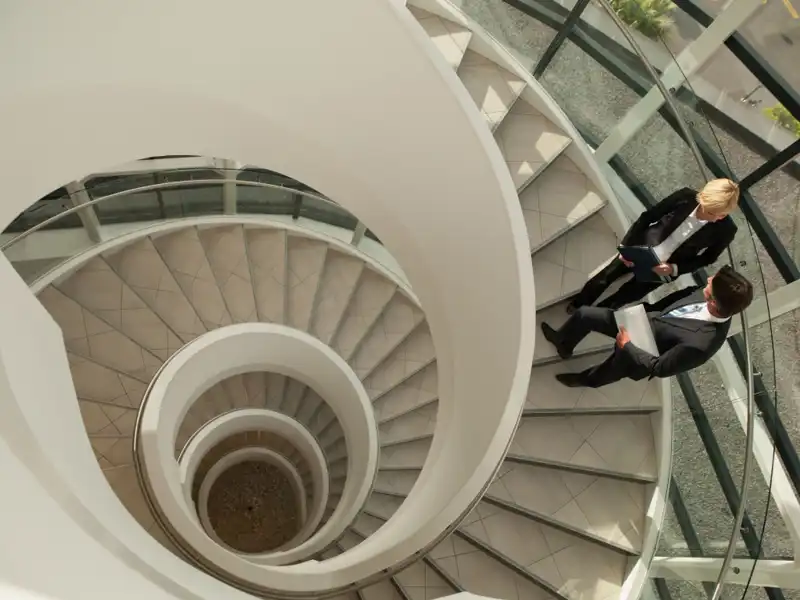 Two people talking on a spiral staircase.