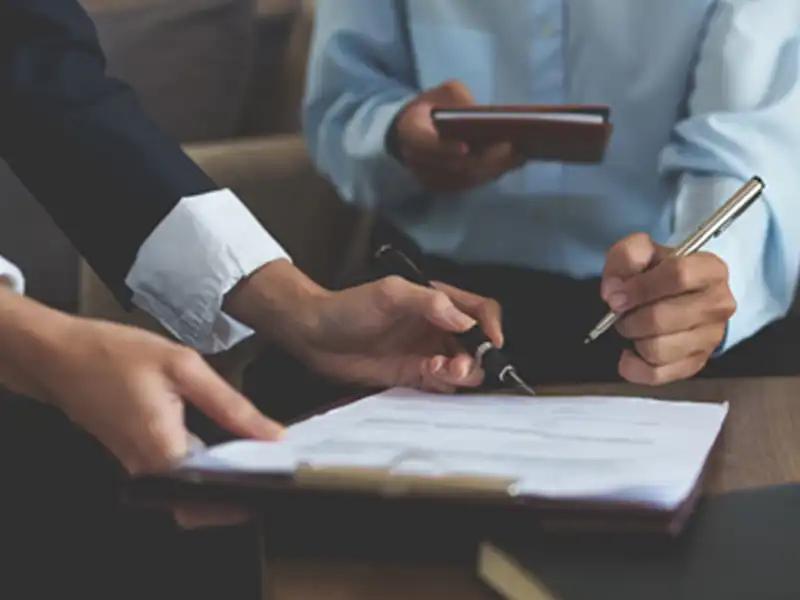 A businessman and client signing paperwork.