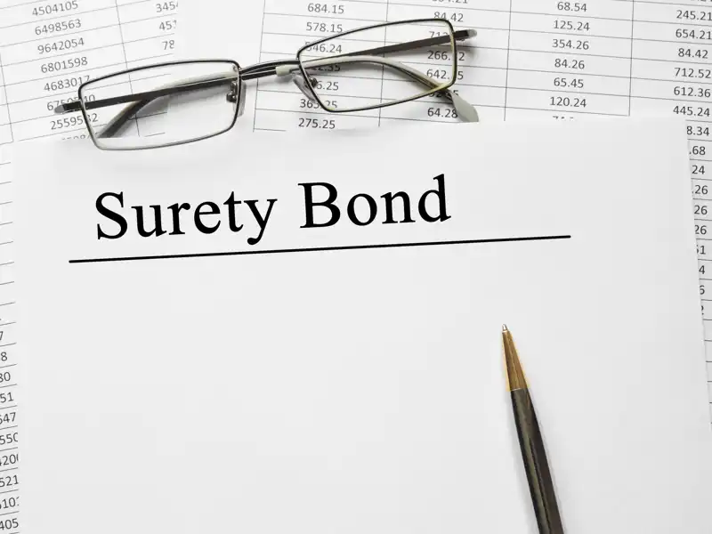 Image of glasses and a pen next to surety bond.