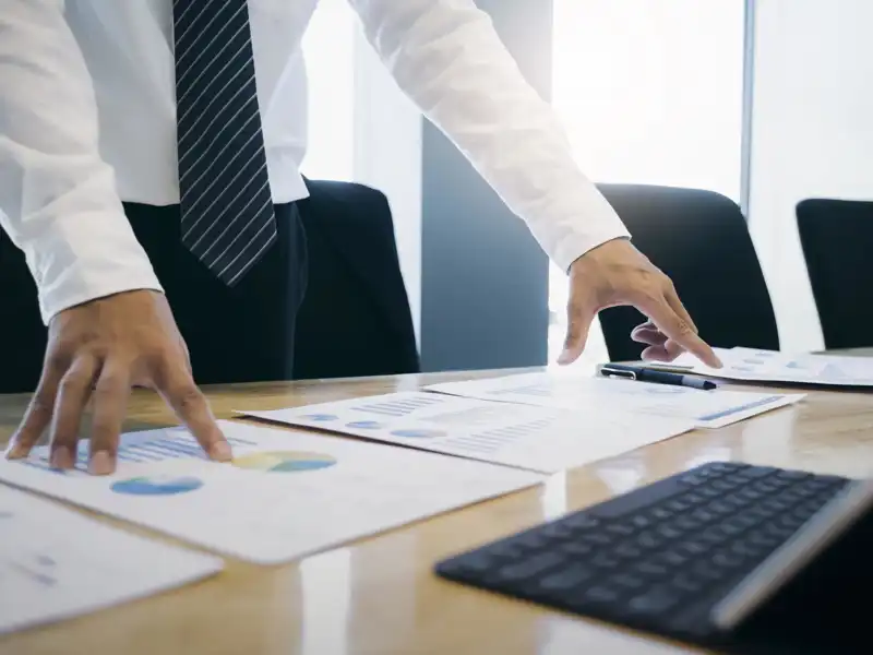 Businessman standing at a desk looking at paperwork.