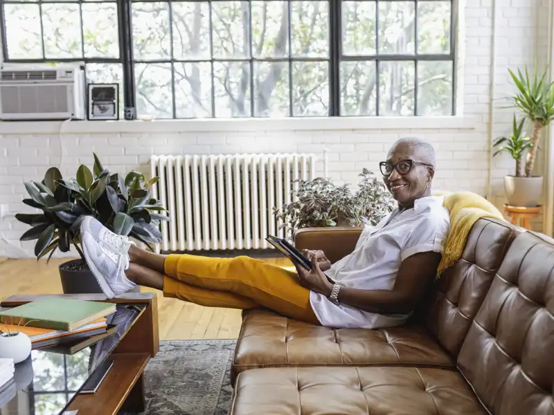 A woman uses a tablet as she relaxes on a sofa