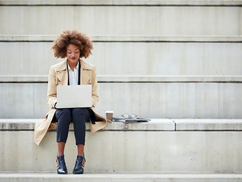 Woman sitting on her laptop outside in a public area