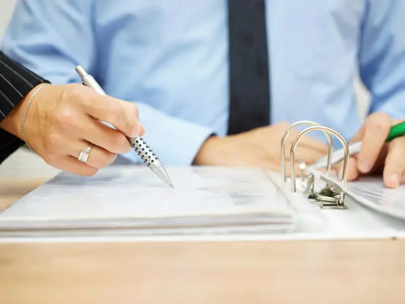 Someone points out a line on a sheet in a binder