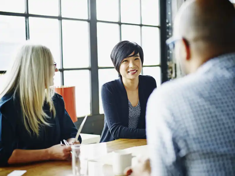 Three people have a friendly discussion at a table