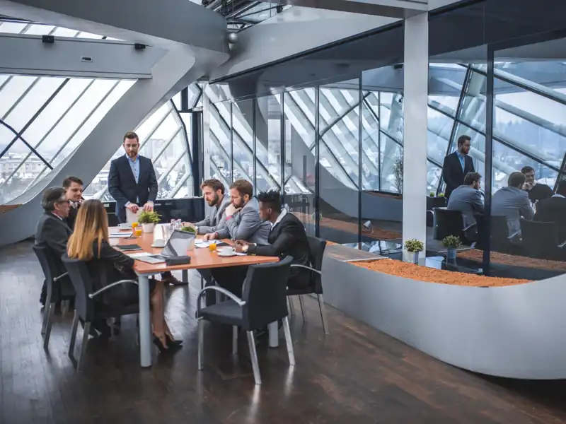 A man addresses a group of business people at a small conference table