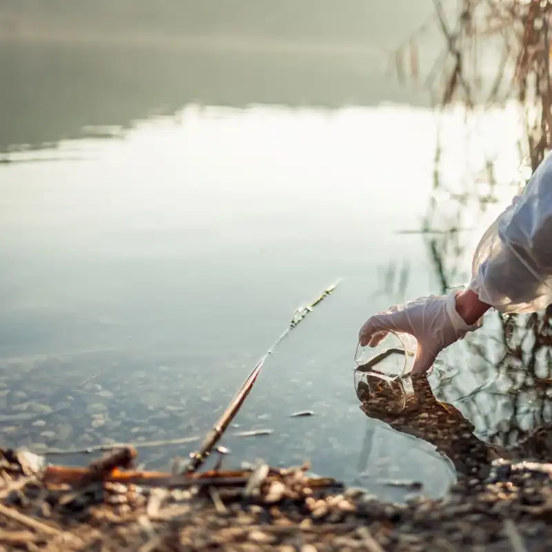 Person taking a water sample from a river.