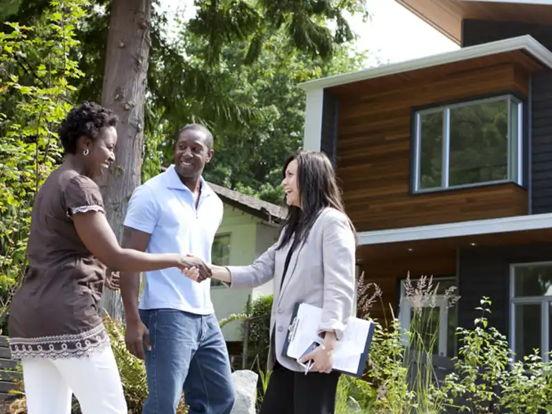 A couple shakes the hand of their realtor at a home closing