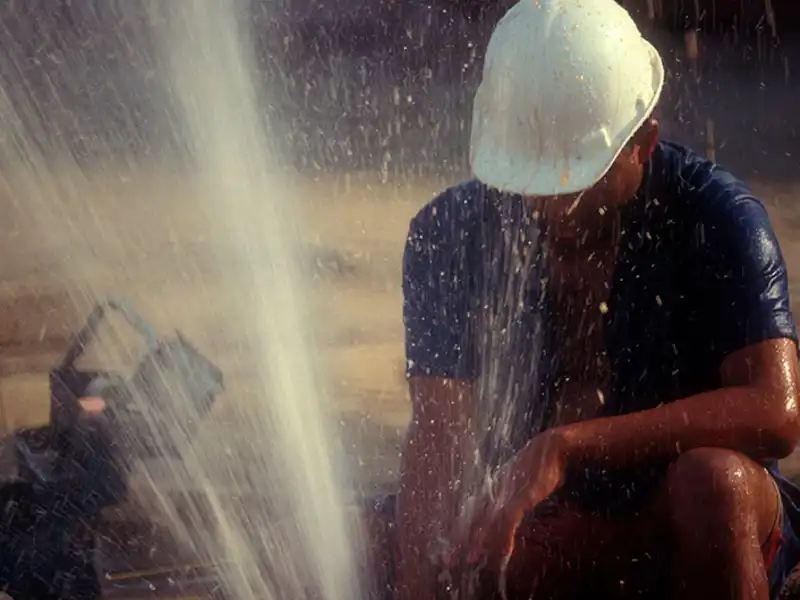 A worker fixes a gushing broken water pipe.
