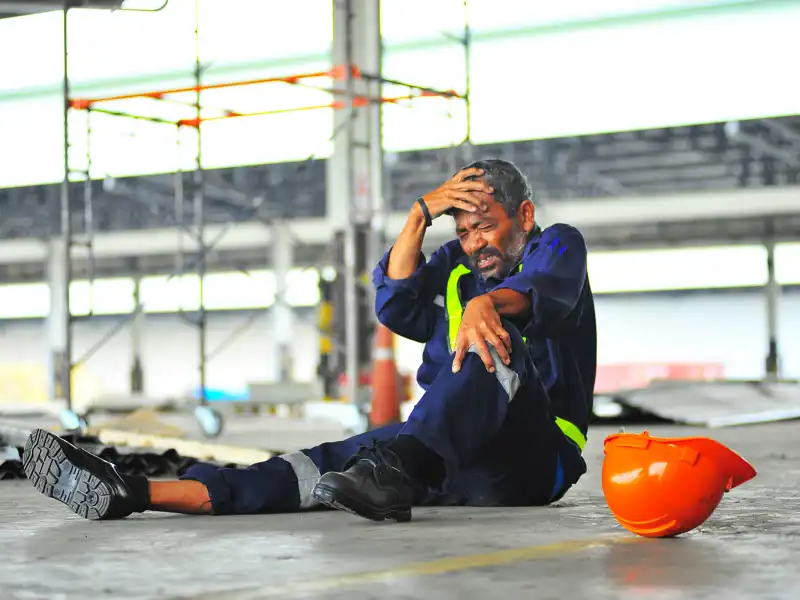 Worker accident fall of the scaffolding and headache with broken leg in construction.