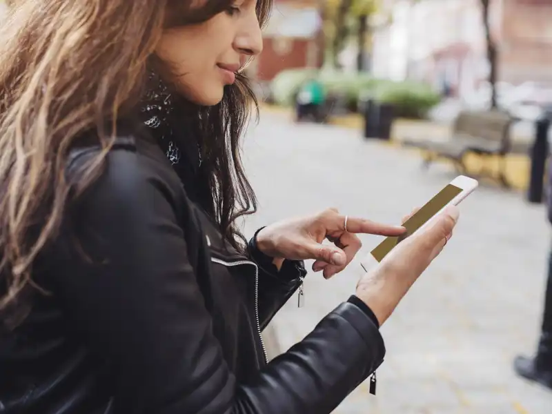 Woman in a black jacket using her cell phone.