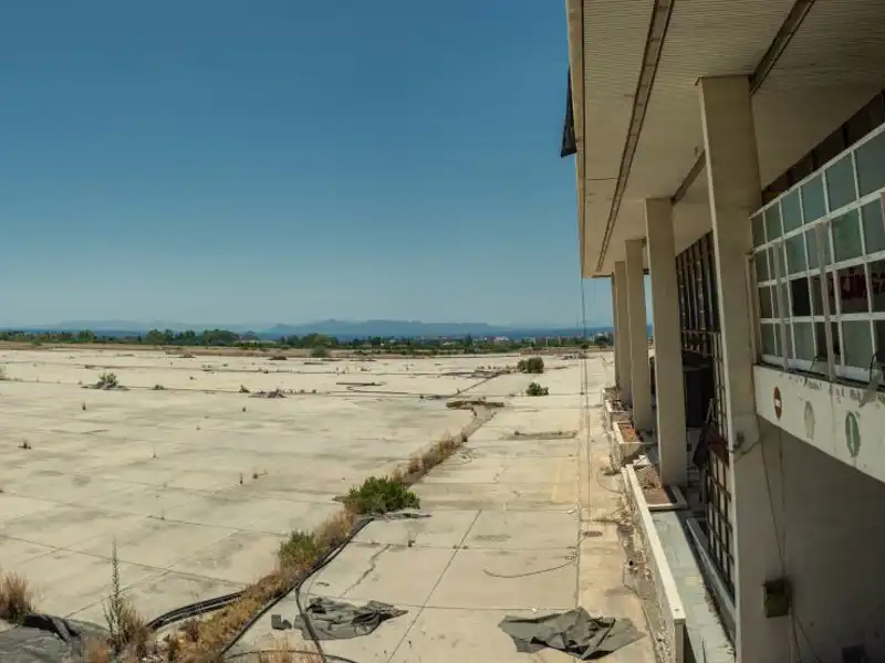 Weeds grow through the empty parking lot of a derelict building