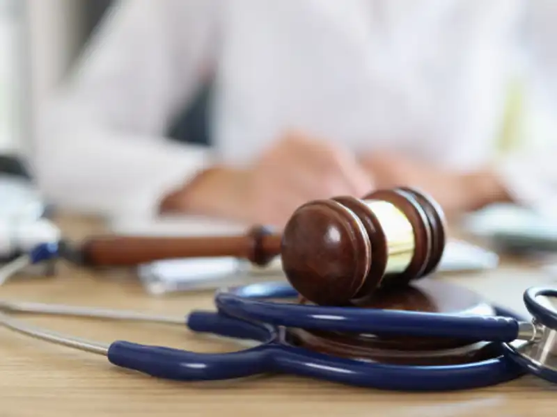 A stethoscope and a gavel placed on a wooden table, symbolizing the intersection of healthcare and law.